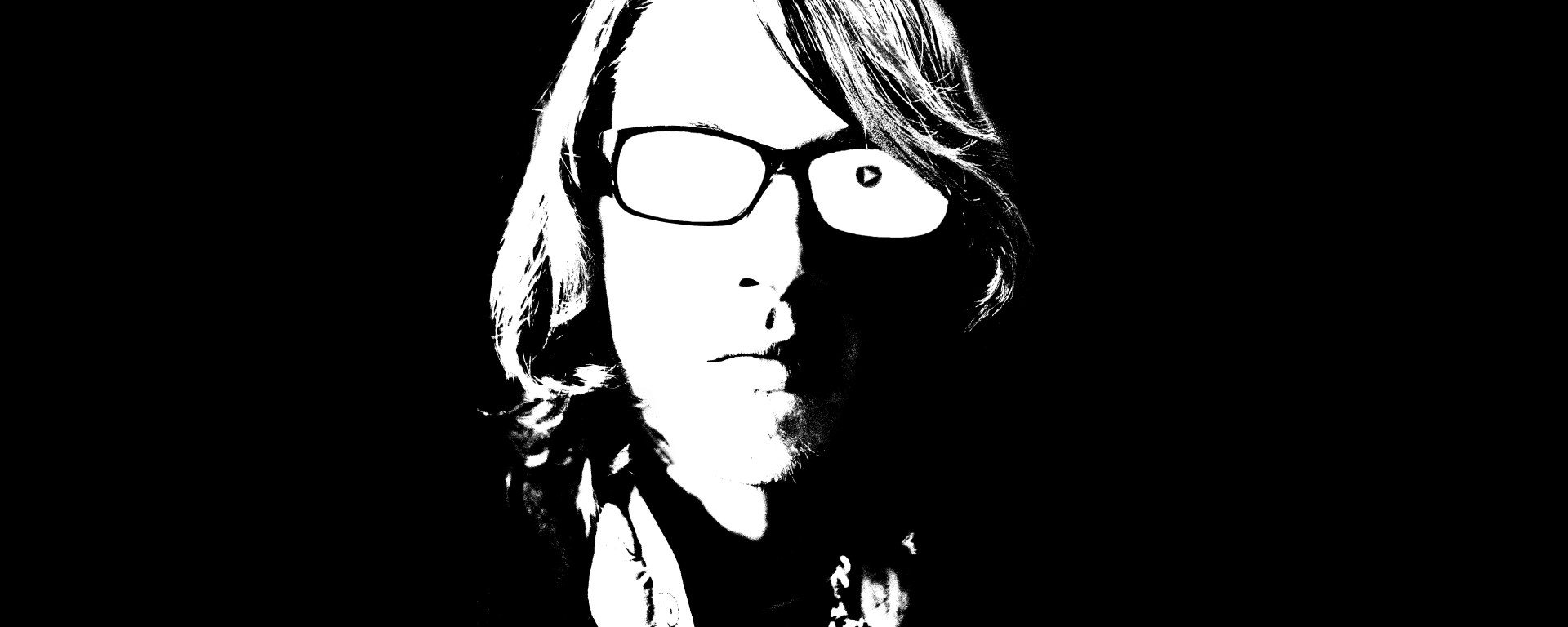 Young man rendered in black and white play button in his eye.