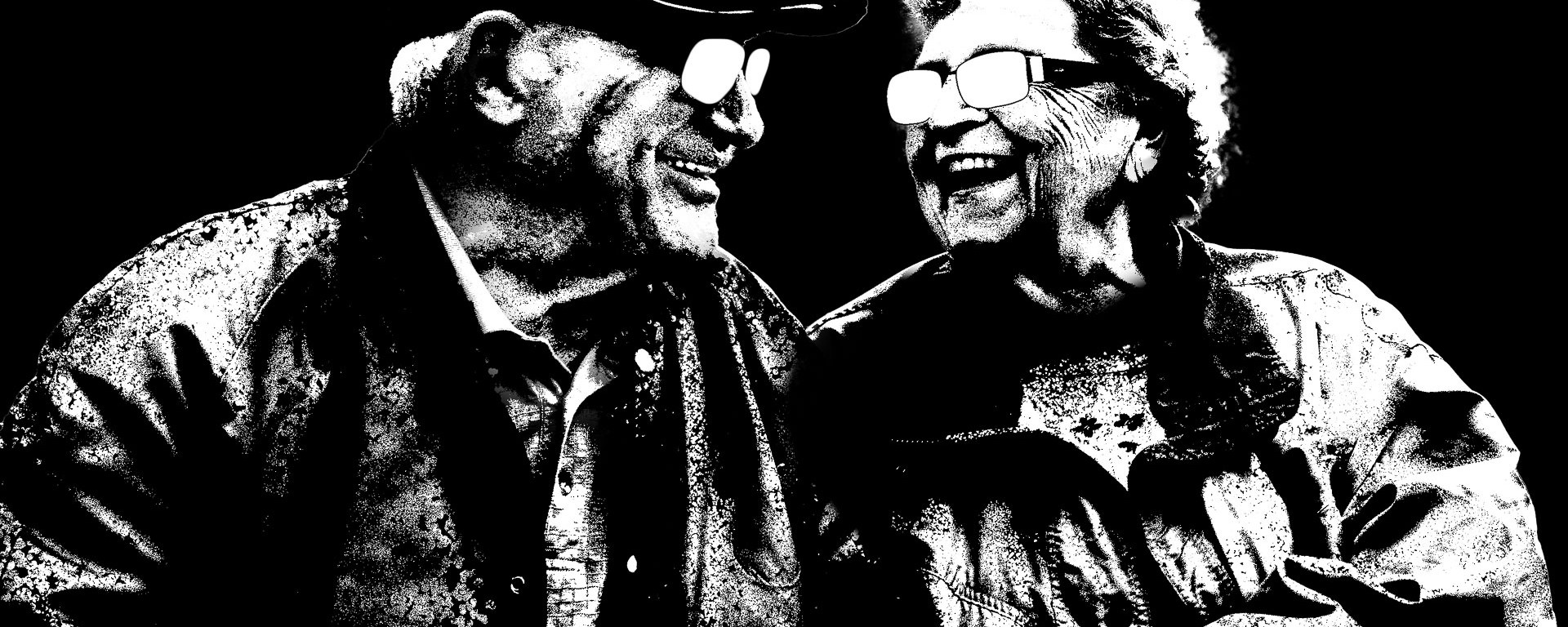 An elderly couple smile at one another, rendered in black and white.