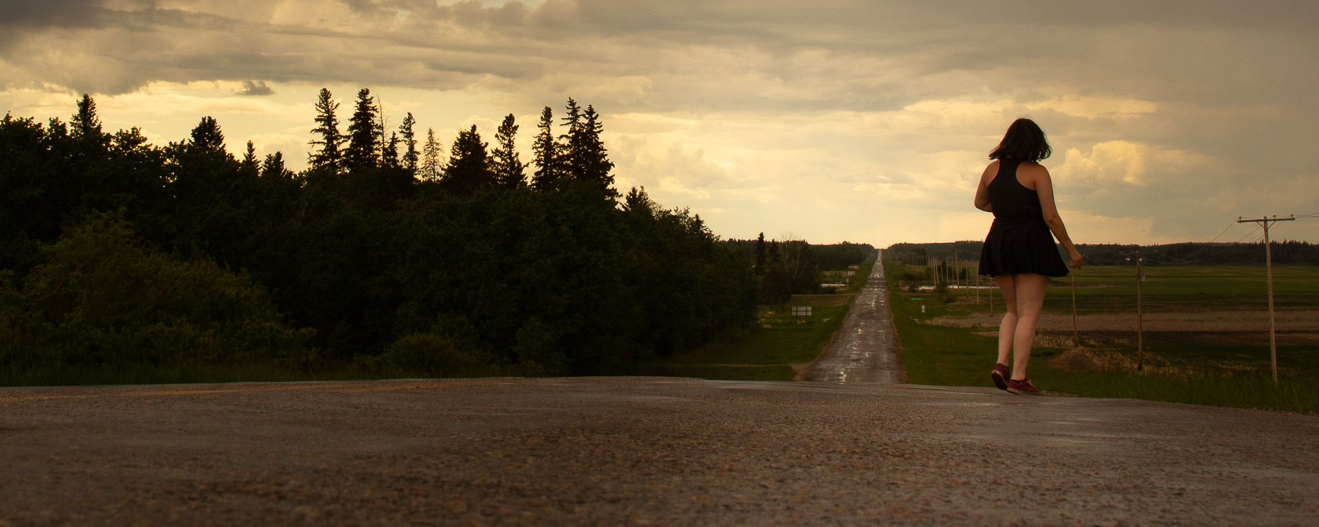 The sun sets on the open road as a woman looks on.