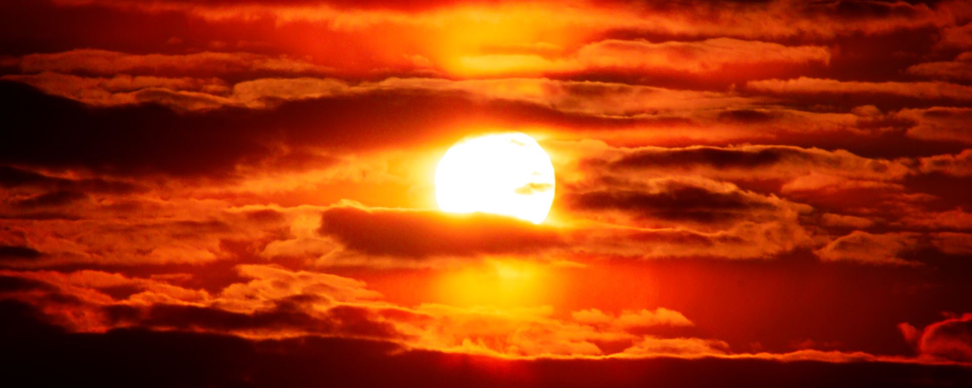 Sunlight glows from behind a cloudy sky.