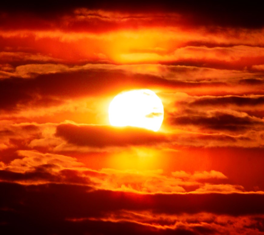 Sunlight glows from behind a cloudy sky.