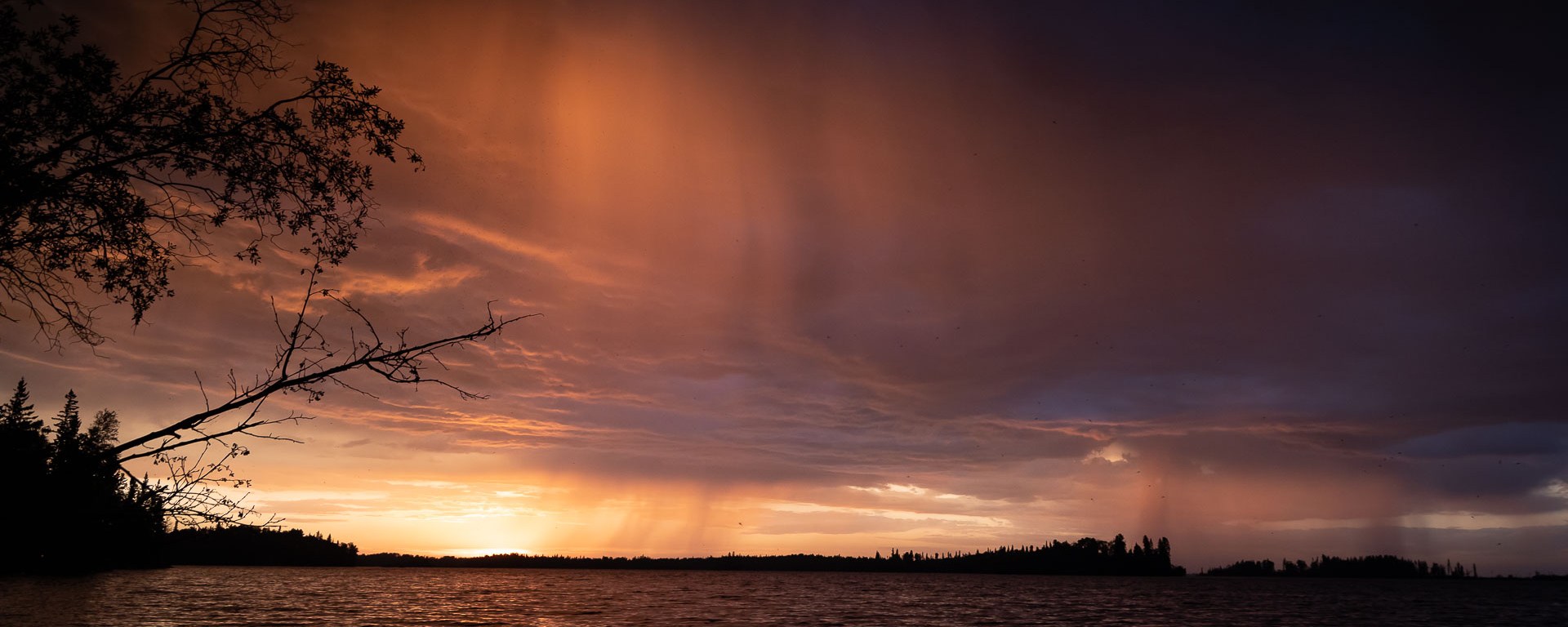 The sun sets before the rains fall upon the lake.