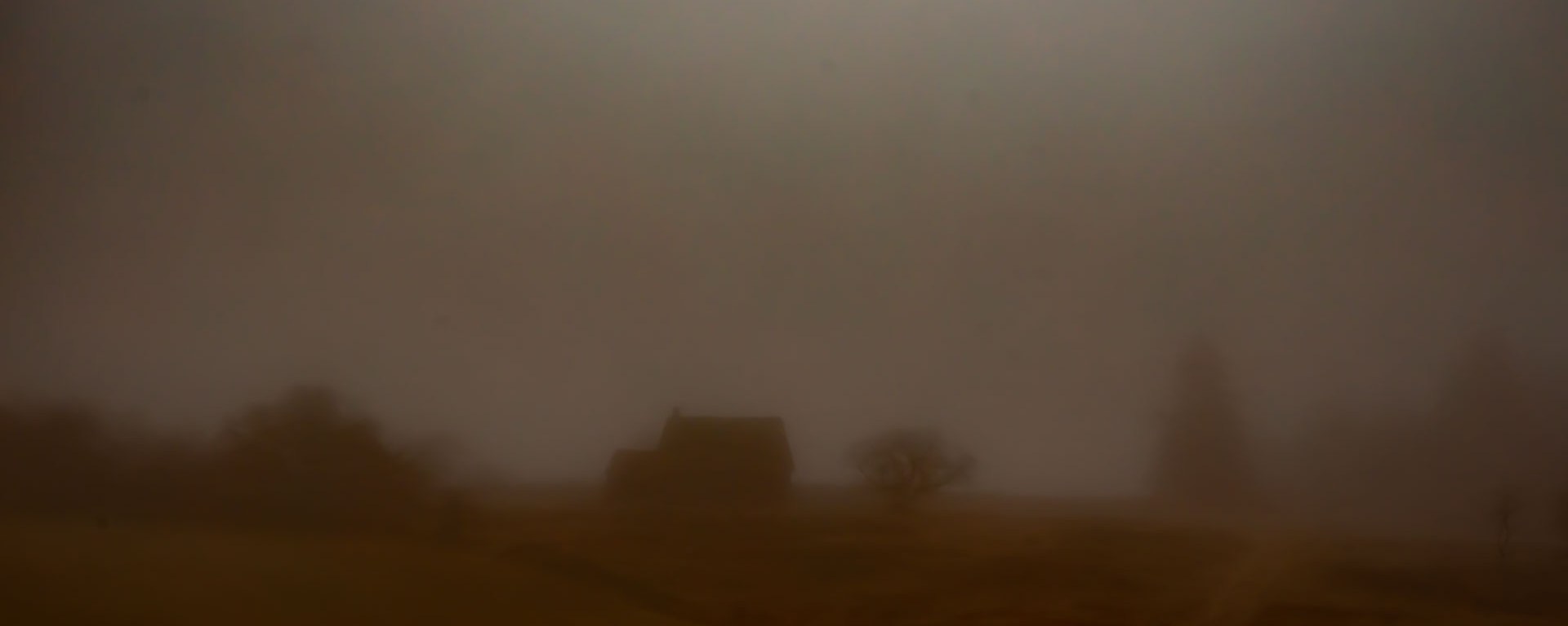 An abandoned homestead sits alone on a hill.