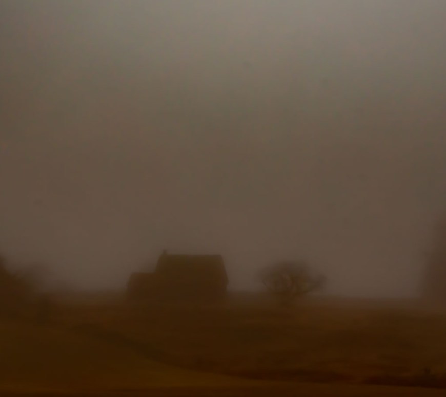 An abandoned homestead sits alone on a hill.