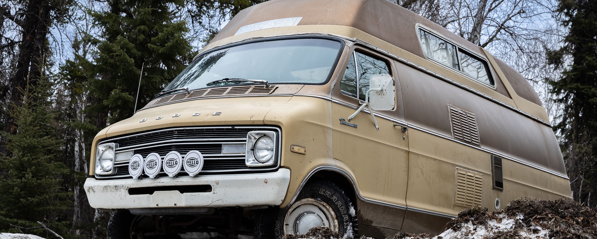 An old camper-van plows through a snowbank.